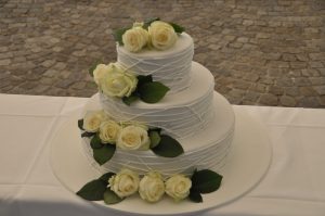 Hochzeitstorte mit echten Blumen und weißen Elementen